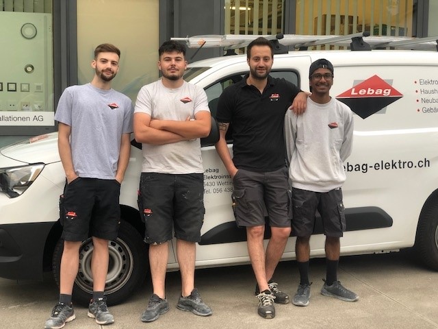 Vier Lernende der Lebag vor dem Lebag-Lieferwagen
