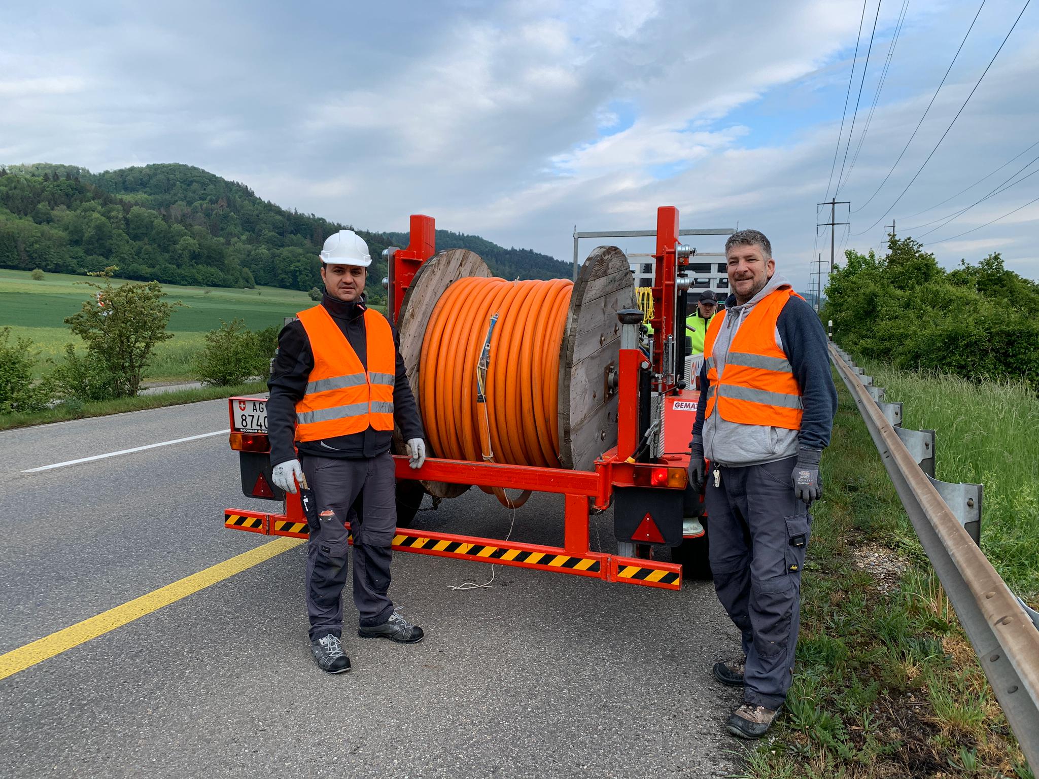 Zwei Lebag-Monteure in Warnwesten vor einer orangen Kabeltrommel an der Strasse